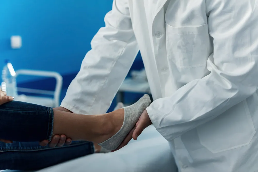 Arzt im weißen Kittel untersucht den Fuß einer Patientin