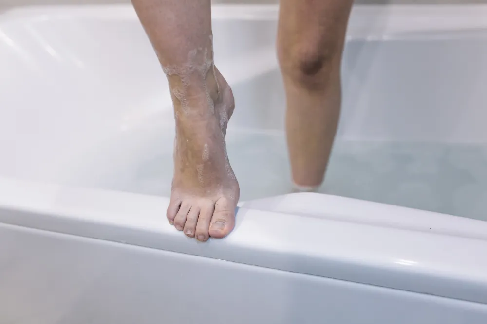 Beine steigen aus einer Badewanne